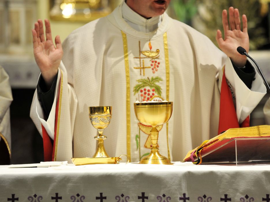 Catholic priest prays at the altar during Mass