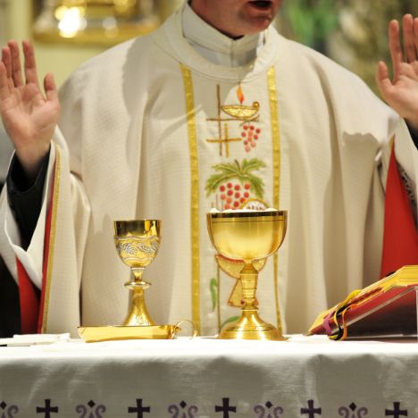 Catholic priest prays at the altar during Mass
